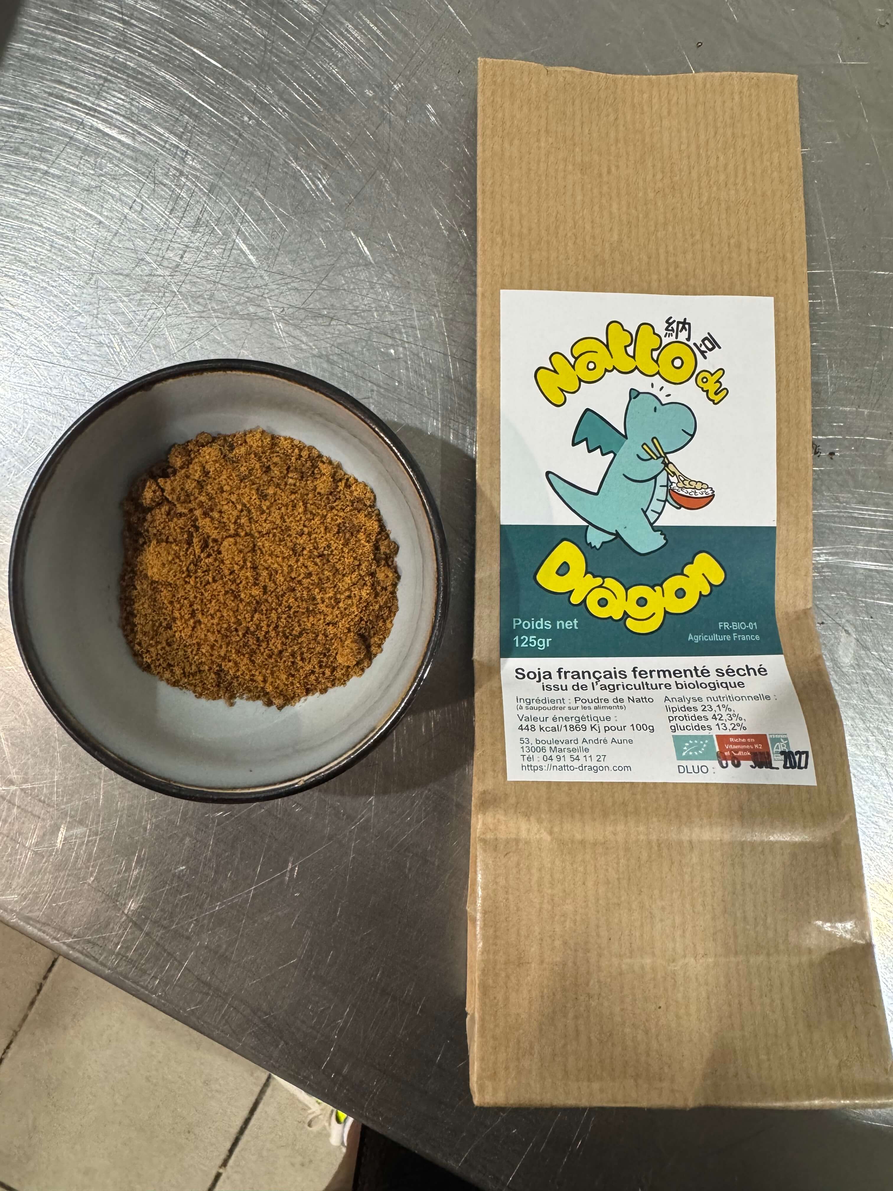 Poudre de natto séchée dans un bol, à côté de son sachet kraft Natto du Dragon